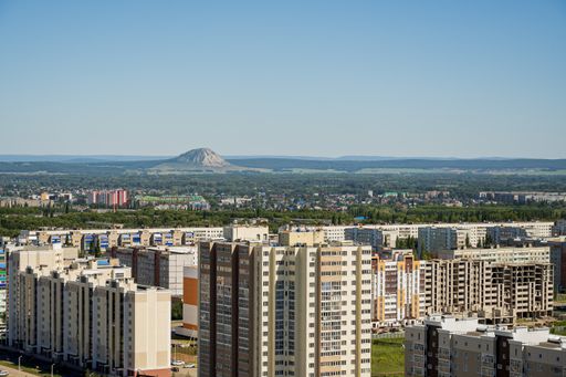 Cityscape aerial view with multi-story residential buildings and relict mountain Shihan Torah Tau in the background. City Sterlitamak, Bashkortostan