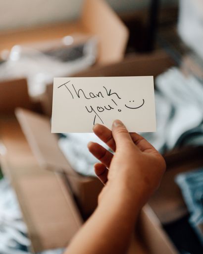 A selective focus shot of a girls hand holding a thank you card - concept of startup business