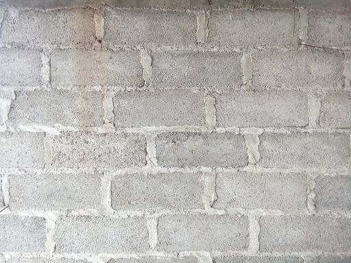 A closeup shot of the wall made up of gray rectangular stones and concrete