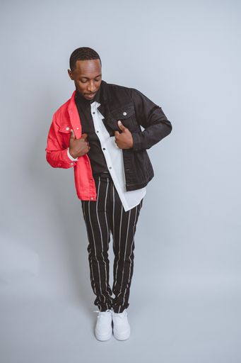 A vertical studio shot of an African American male model posing in colorful fashionable clothes