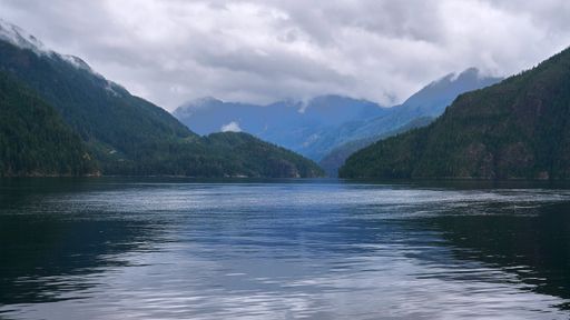 Looking down a long Pacific Northwest inlet on a moody day as the clouds roll down the distant mountains.