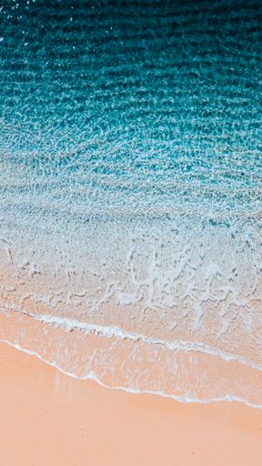 A beautiful aerial top view of sea waves washing the shore