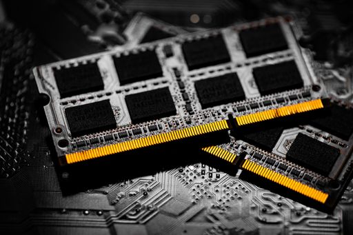 A closeup of the computer RAM chip and motherboard on dark background