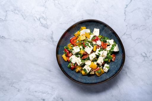 A top view of a delicious healthy Greek salad with feta cheese on a marble table