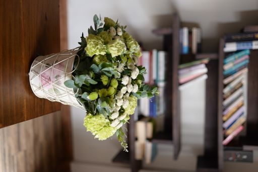 A vertical shot of a decorative vase with a green-white bouquet in a living room