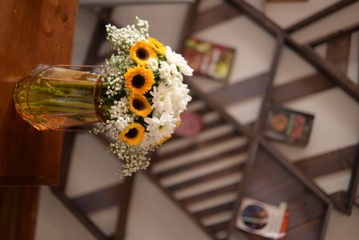 A vertical shot of a decorative vase with white flowers and sunflowers in a living room