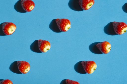 A high angle shot of cleaned strawberries on a blue surface under the sunlight