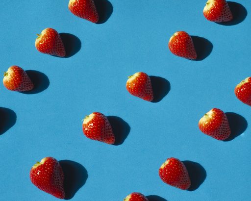 A high angle shot of cleaned strawberries on a blue surface under the sunlight