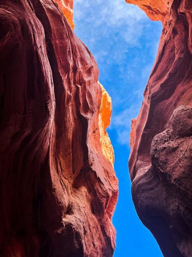 A vertical low angle shot of a cloudy sky seen through the cliffs