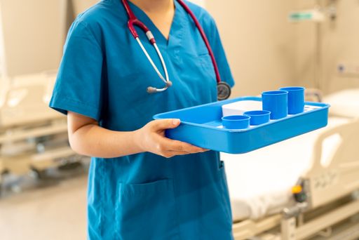 A female nurse in a uniform holding a tray of plastic laboratory equipment
