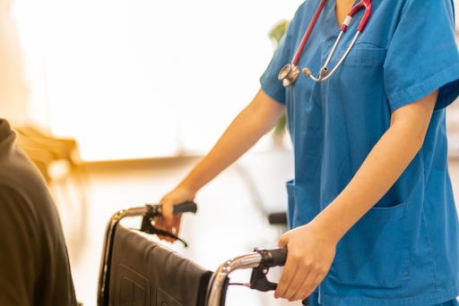 Unrecognizable female doctor helping disable patient with wheelchair-work concept
