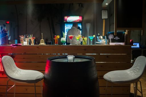 A row of different martini glasses on the counter in a bar with an empty table in front of it.