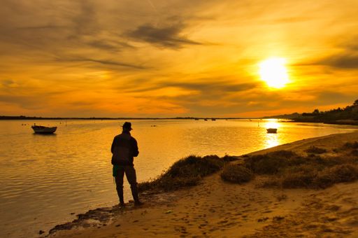 A silhouette shot of a man standing on the seashore