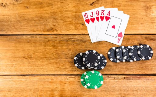 A top view of stacks of poker chips and cards on wooden background