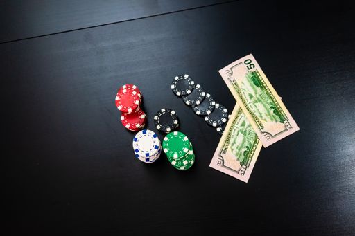 A top view of stacks of poker chips with money on a black table