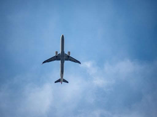 A scenic view of an airplane flying in the blue sky