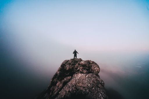 An aerial shot of a male on the top of a mountain on blue background