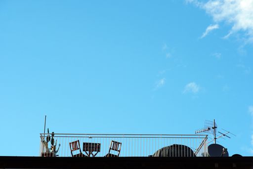A beautiful shot of the rooftop with two chairs under on a blue sky