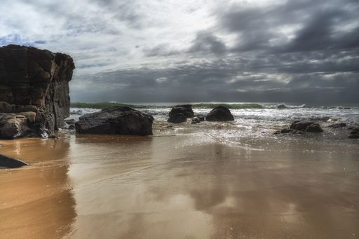 A beautiful shot of a small cliff and rocks beach under the cloudy sky