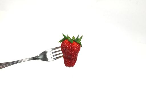 A closeup shot of a strawberry on a fork isolated on a white background