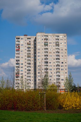A vertical shot of tall apartment blocks near a green grass field in the Orla Bialego district