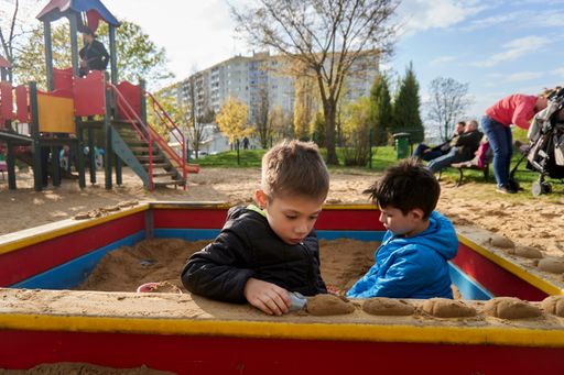 A selective of two young boys playing with plastic toys in a sandpit at a playground