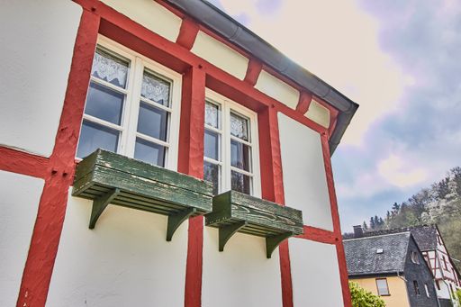 A vertical exterior traditional building with windows in the old village Monreal buildings, Germany with a blue cloudy sky