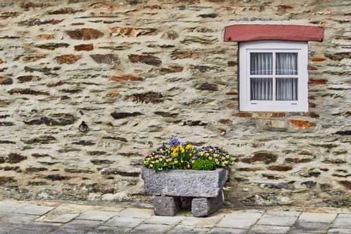 A beautiful exterior old stone wall building with a window and plants in the old village of Monreal, Germany
