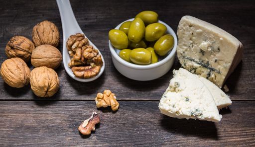 roquefort cheese with walnuts and olives on dark background