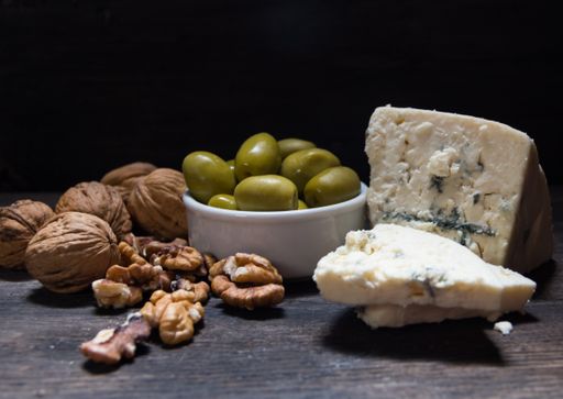 roquefort cheese with walnuts and olives on dark background