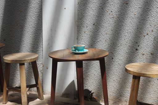A horizontal shot of small wooden tables with a single coffee cup on it