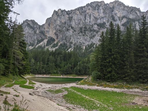 A lake in the middle of the forest with mountains against a gloomy sky in the background