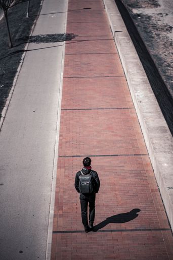 A vertical shot of a young man walking on the road