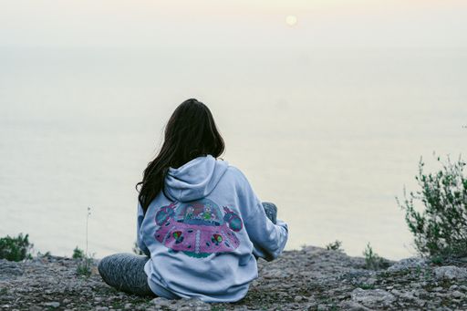a young woman wearing a Rick and Morty hoodie at the Es Vedra viewpoint in Ibiza, Spain.
