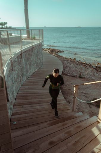 A vertical shot of a young Latino female climbing up the stairs during her running routine