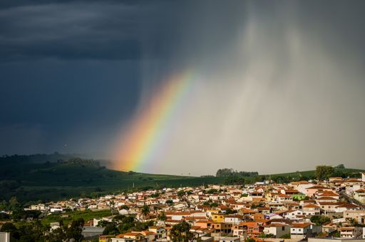 An aerial shot of a small town and forested hills underneath the rainbow