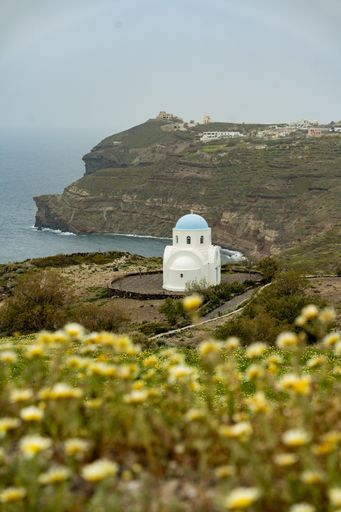 A vertical shot of a white cathedral on the hillside of Santorini