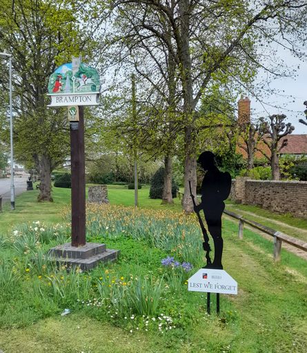 A vertical shot of the village sign and war memorial in Brampton, Cambridge