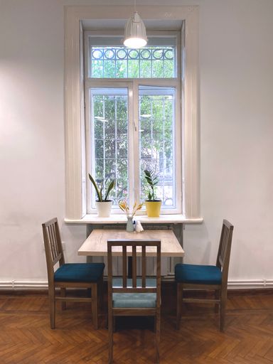 A vertical shot of a room interior with a table and chairs near a windoe