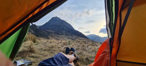 A beautiful shot of a hiker's feet from a camping tent to the Glyder Fach mountain peak