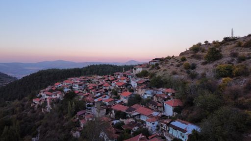 An aerial view of beautiful small buildings in the mountains with a colorful sunset in the sky