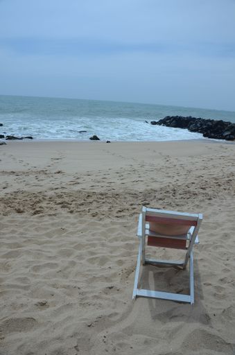 A vertical shot of a beach chair on a sandy coast