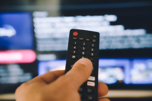 A male hand holding TV remote control
