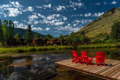 Red outdoor chairs by a lake with a mountain as a backdrop in Jackson, Wyoming, USA.