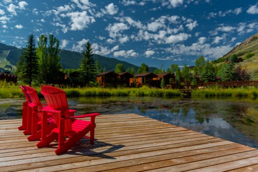 Red outdoor chairs by a lake with a mountain as a backdrop in Jackson, Wyoming, USA.