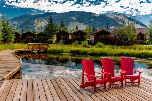 The three red chairs near the lake with houses and mountains in the background in Jackson, Wyoming