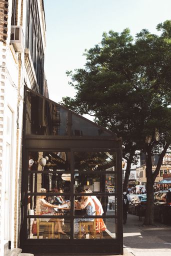 Vertical photo of a New York City cafe with dine-in seating on a patio.
