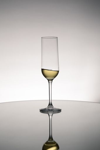 A glass cup of wine with reflection on a mirror surface