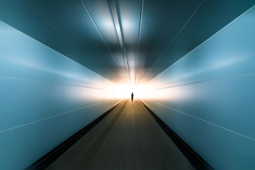 silhouette of running man toward ending with sunshine ahead in motion blurred tunnel, business success concept.