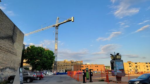 A beautiful view of a crane and a playground with parked cars under the blue sky